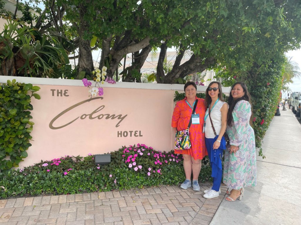 tres planificadores de reuniones delante del cartel del hotel The Colony