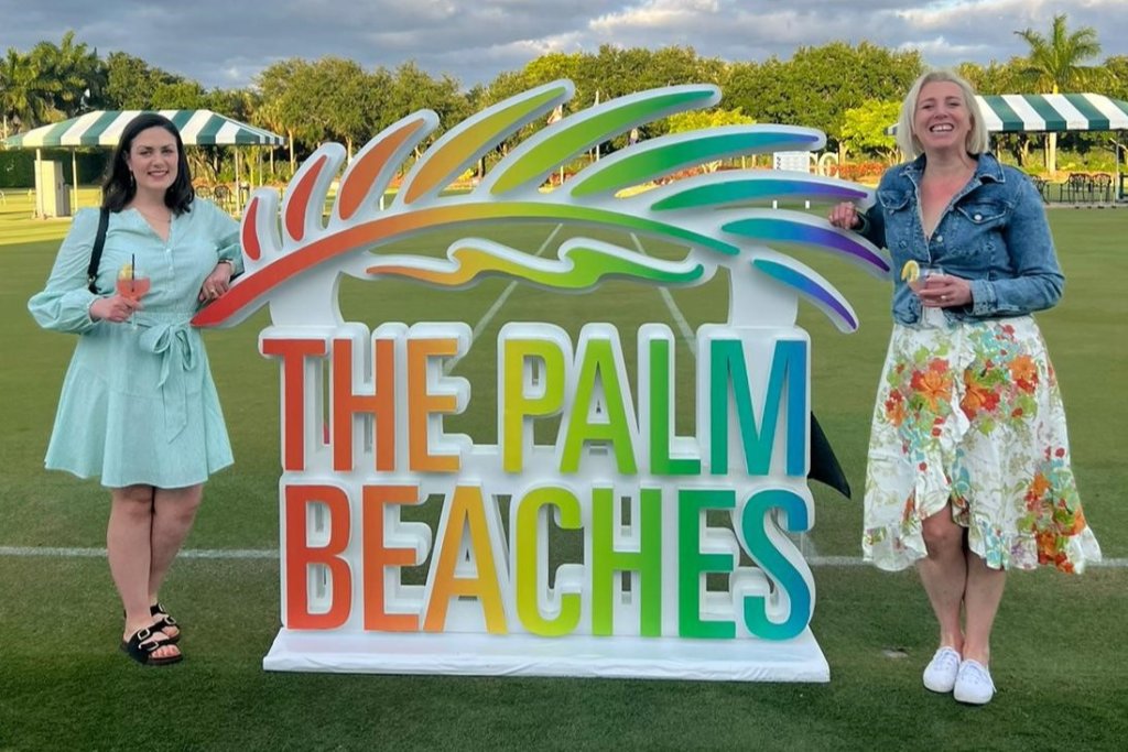 Deux femmes debout à côté du panneau The Palm Beaches 